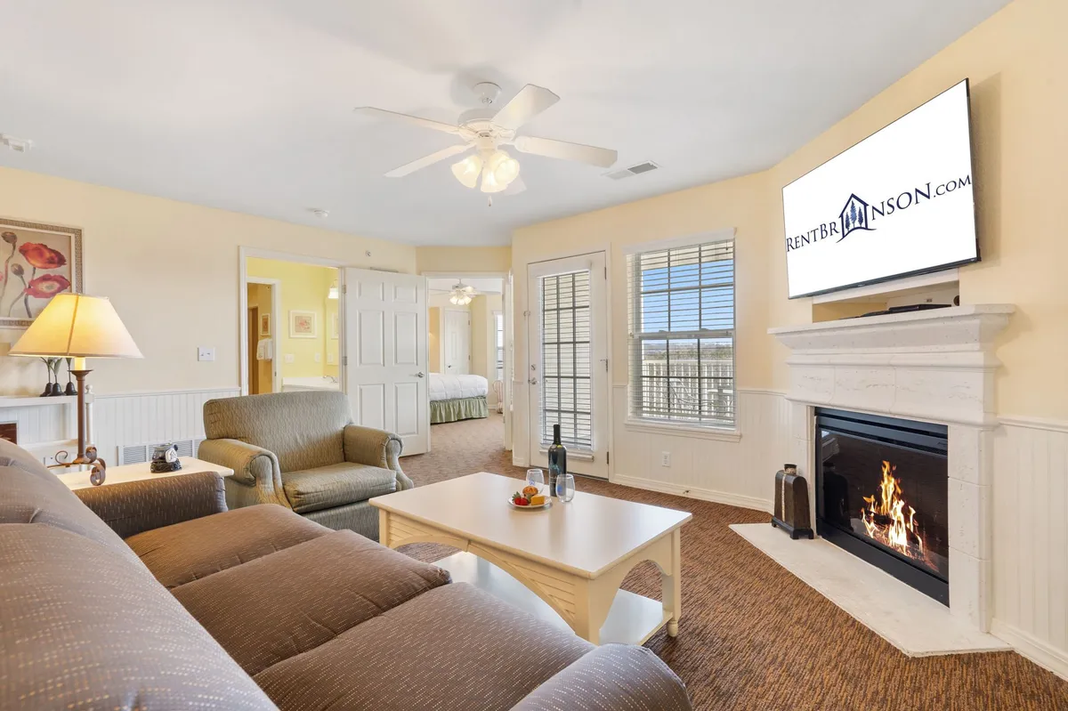 A warm, inviting living room centered around a cozy electric fireplace, complete with a plush sofa, coffee table, and television. The soft lighting and comfortable furniture create a welcoming space for relaxation, socializing, or enjoying a movie night.