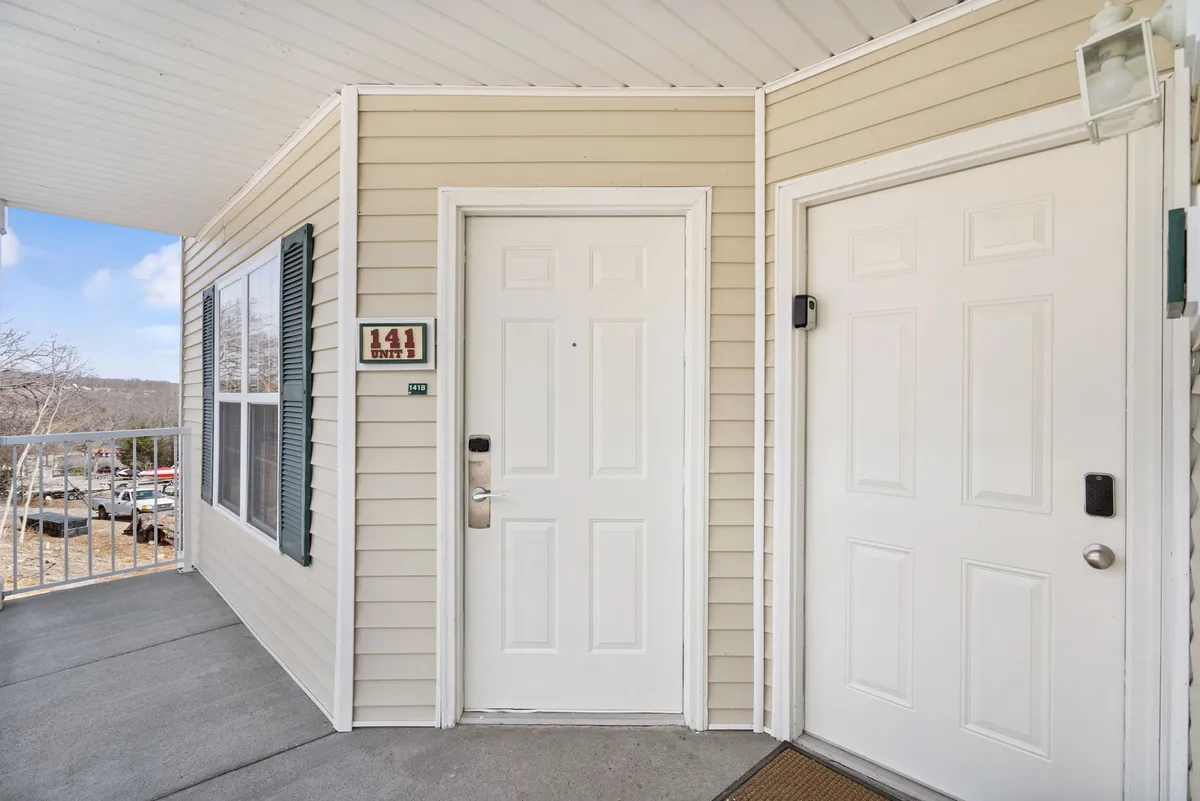 A welcoming exterior shot of the condo's main entrance, with unit number signage, doors, and windows visible. The image conveys a sense of arrival and the transition from outdoor adventures back home.