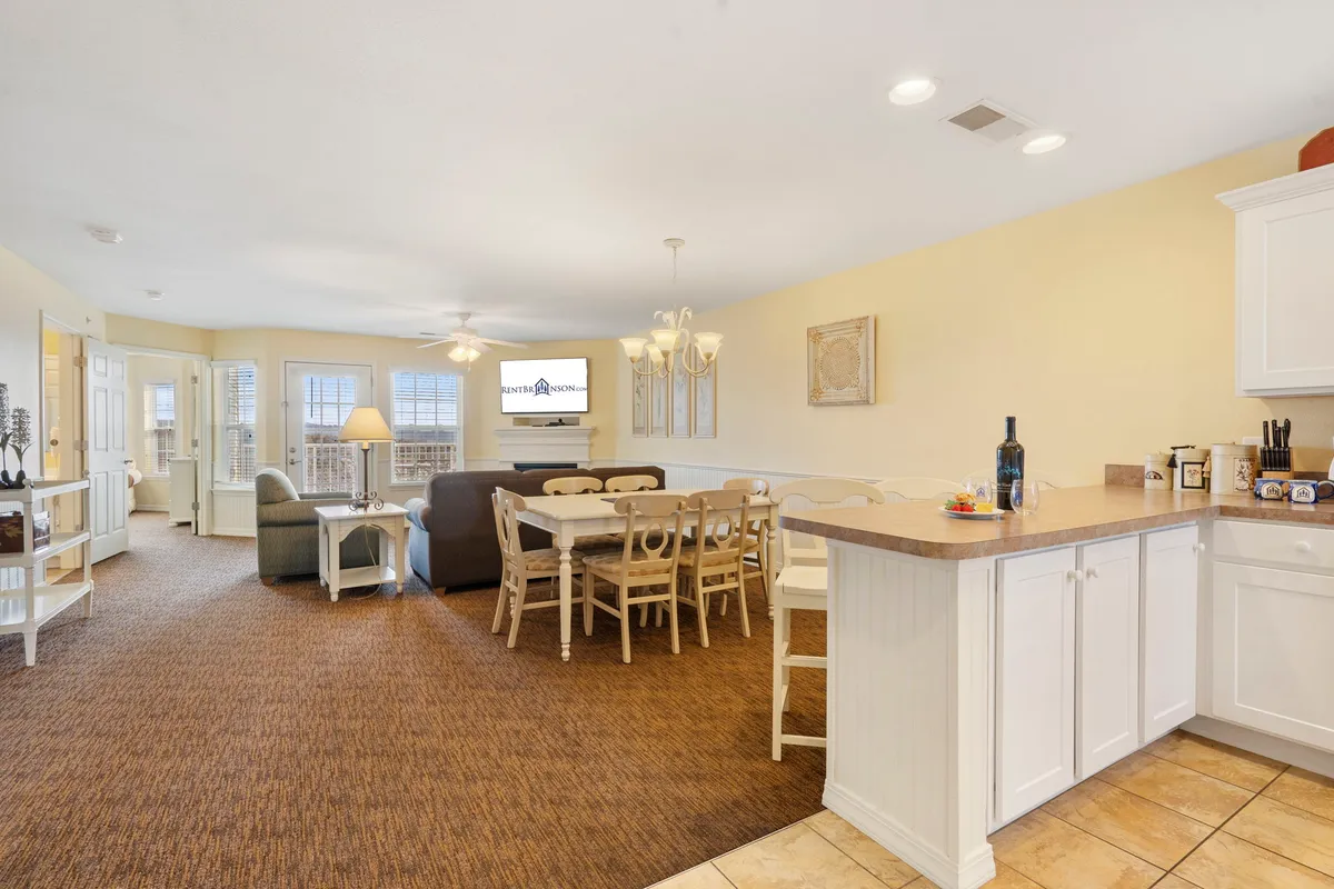 An open-concept layout featuring a dining table, comfortable seating area, kitchen counter, and television. The space flows naturally, inviting shared meals, engaging conversations, and casual relaxation—all in one welcoming area.