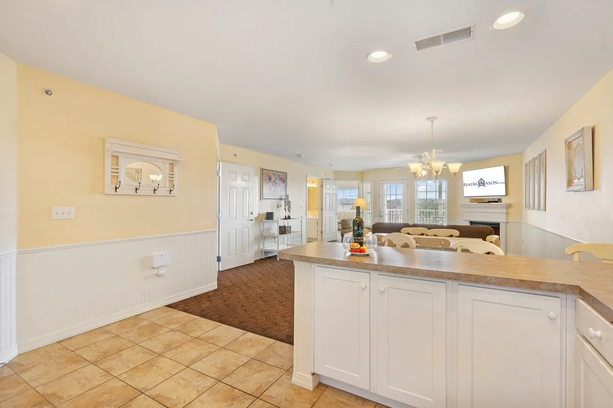 A view of the kitchen island and adjacent dining area, accented by stylish light fixtures and decorative wall art. The space feels inviting and ready for gatherings, with ample room for cooking, conversation, and celebrations.